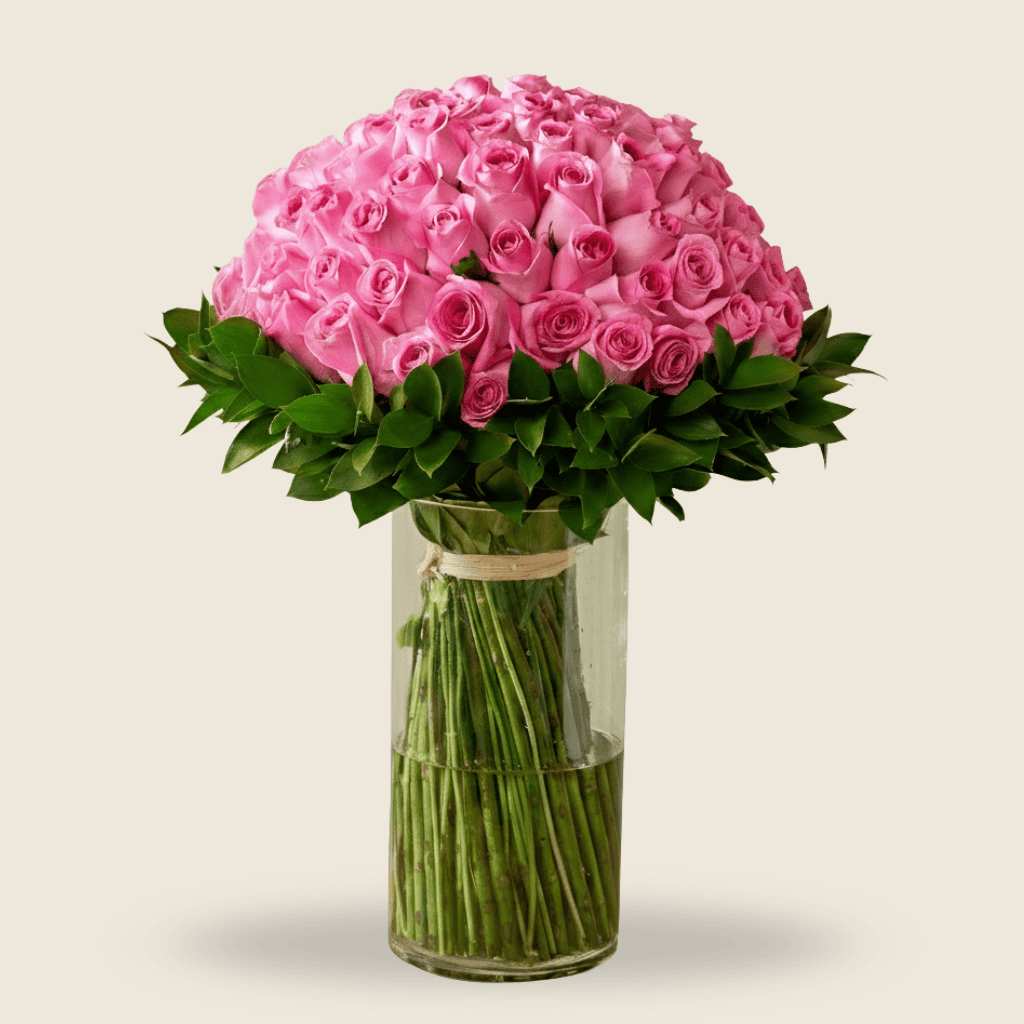 Tall vase of pink roses with lush green leaves