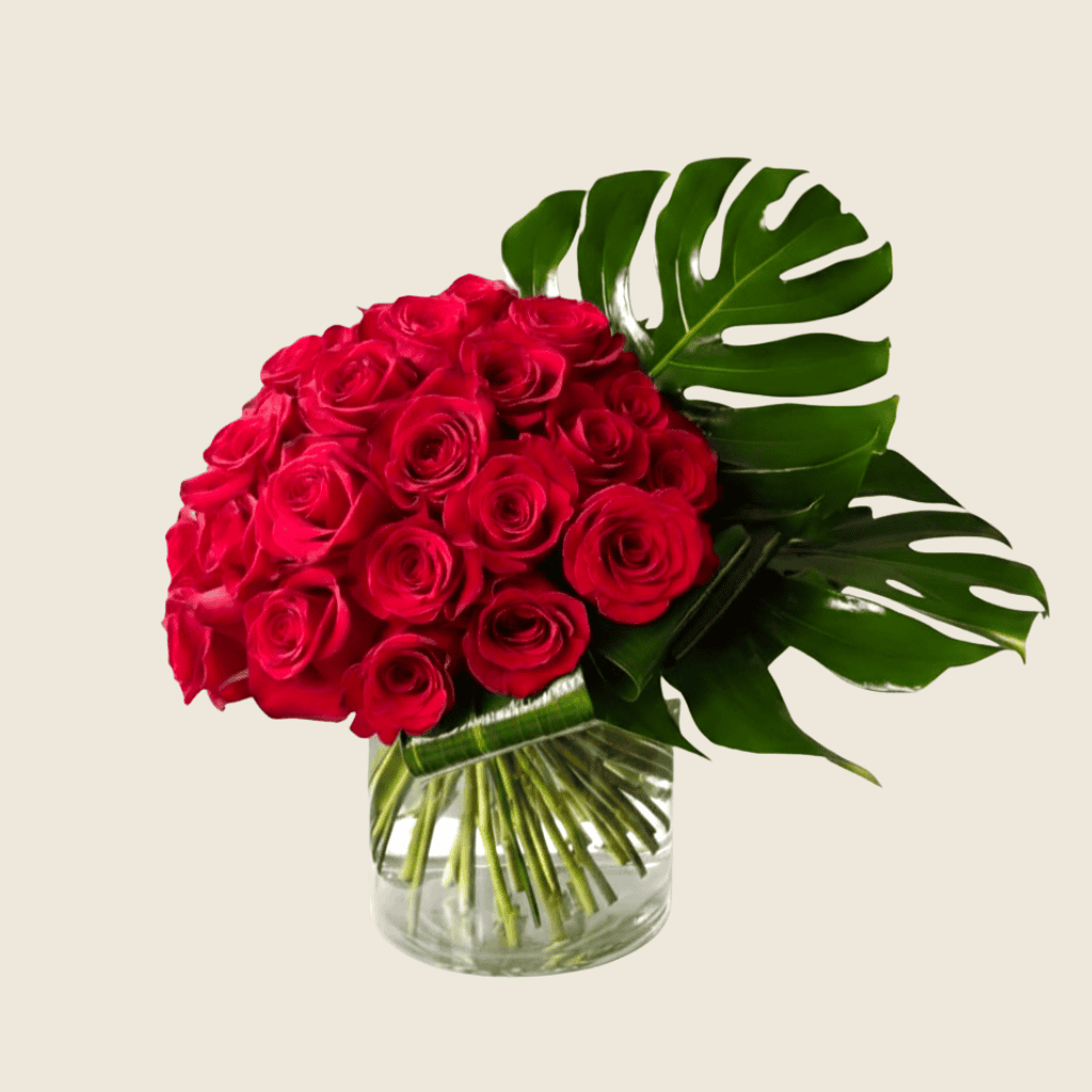 Modern vase arrangement of red roses with monstera leaf accent