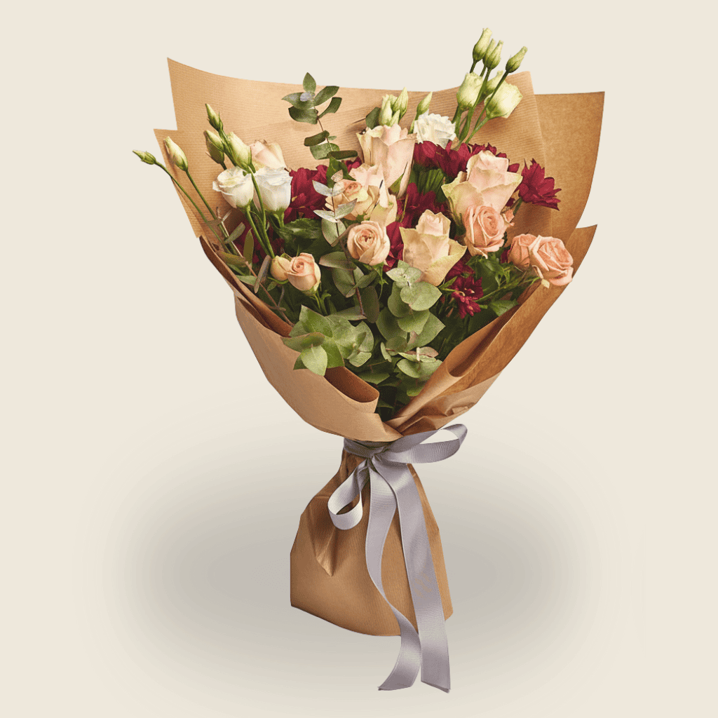 Handheld rustic bouquet with blush roses, burgundy blooms and kraft paper wrap